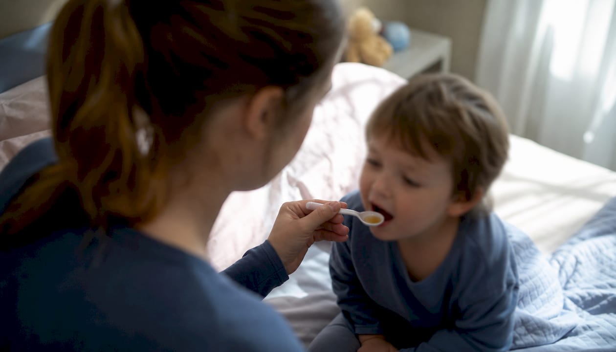 Een ouder geeft zijn kind melatoninesiroop om beter te kunnen slapen.