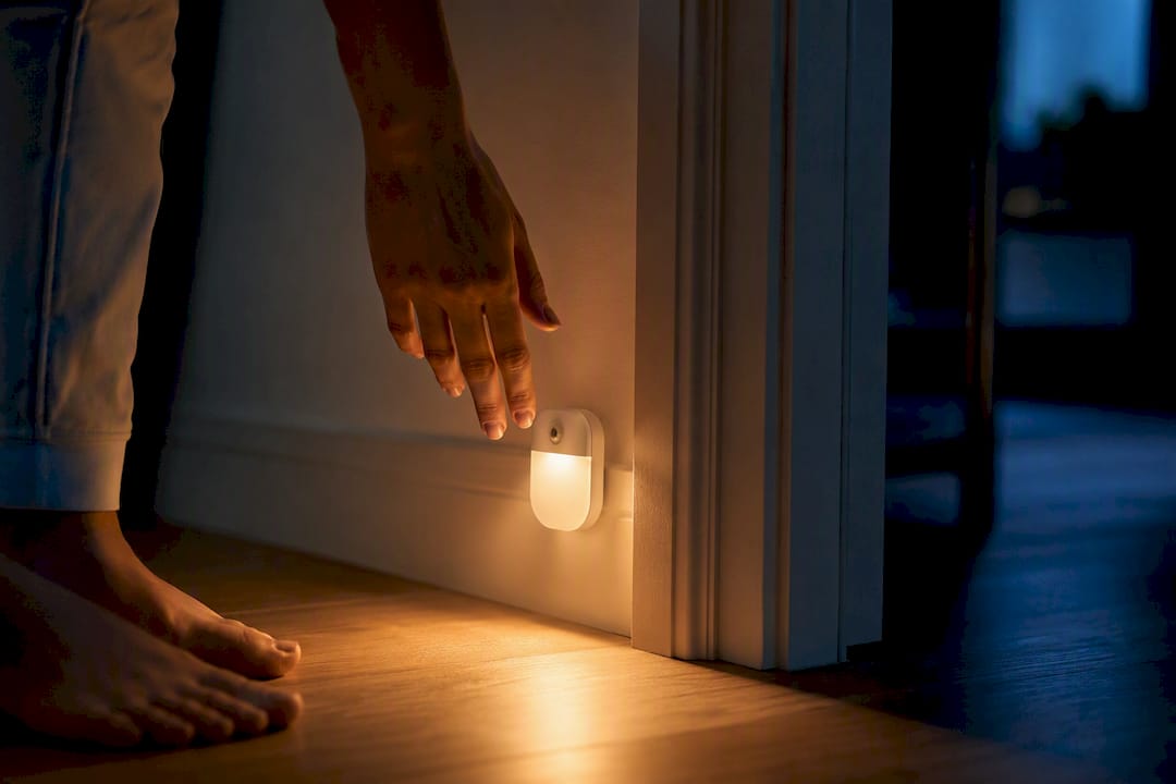 Hand die warm nachtlampje bij slaapkamerdeur aanzet